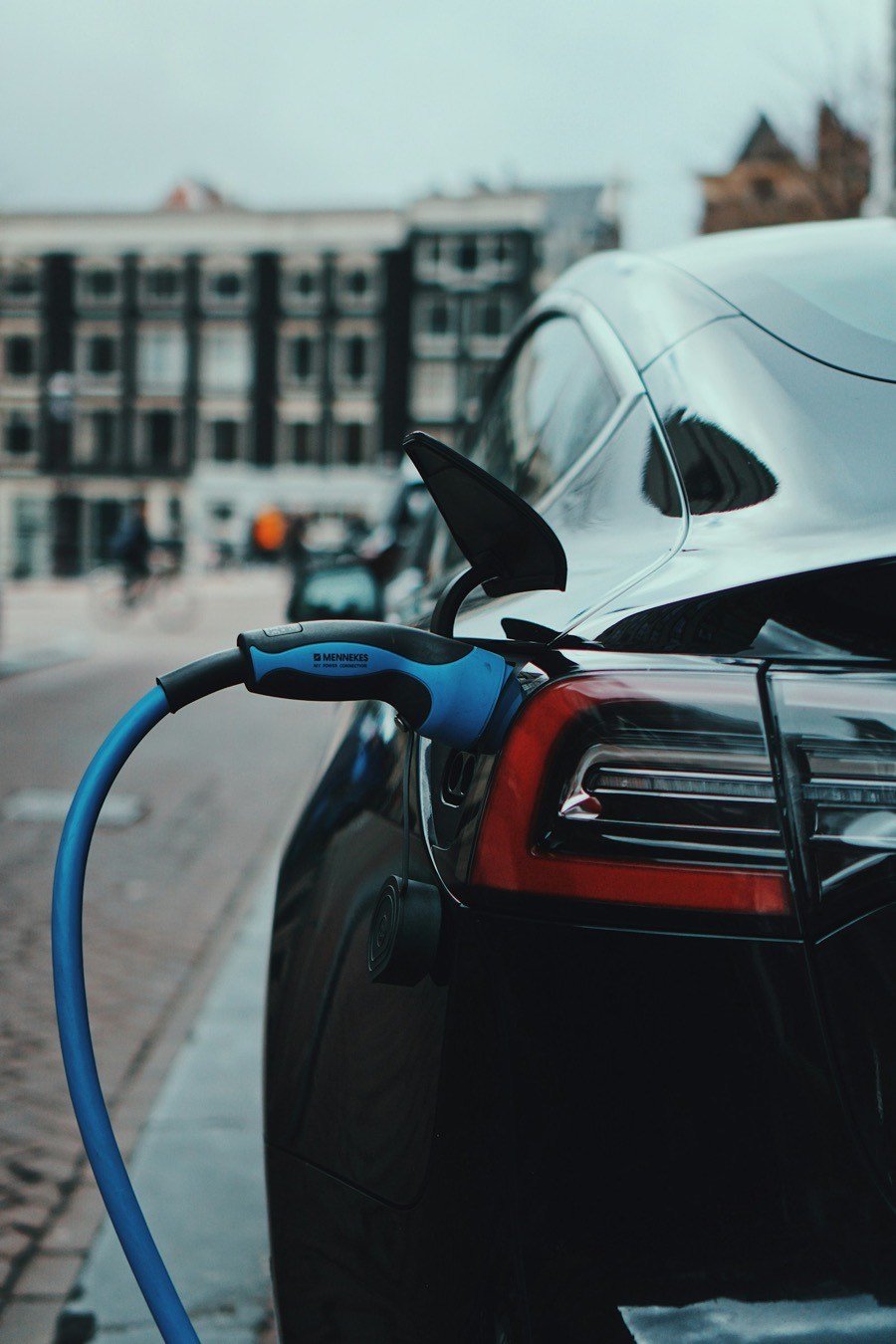 Véhicule électrique en charge en ville, devant un immeuble